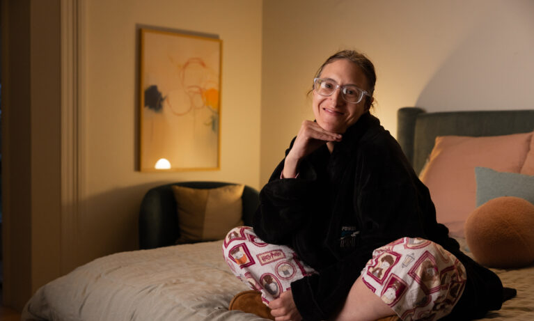 Short Term Respite Client smiling and sitting on a bed at Myranth House.