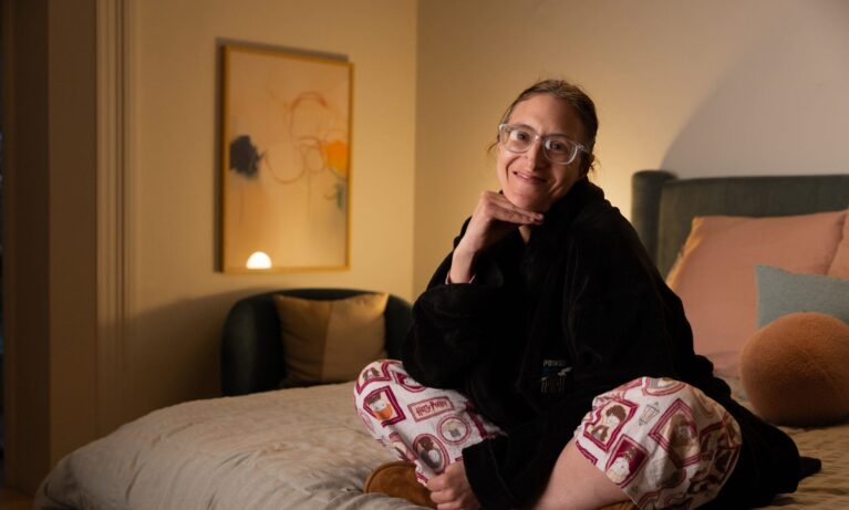 Short Term Respite Client smiling and sitting on a bed at Myranth House.