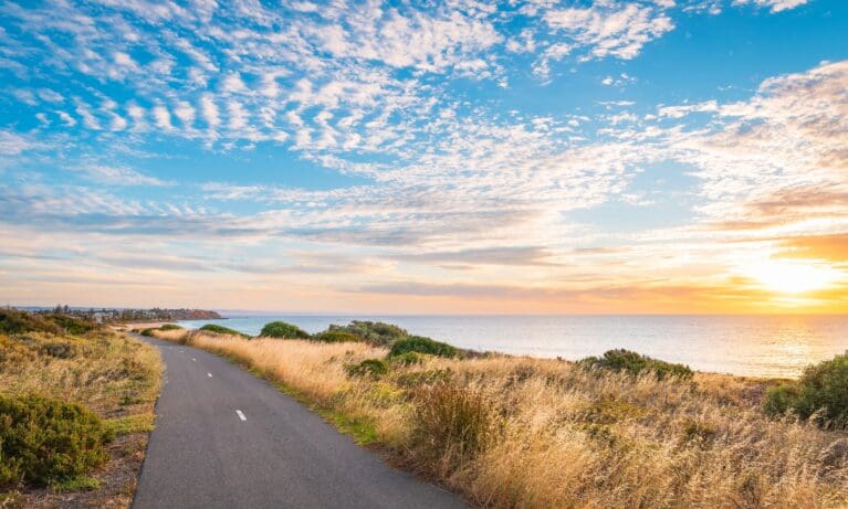 Beach at sunset with a road running alongside the shoreline.