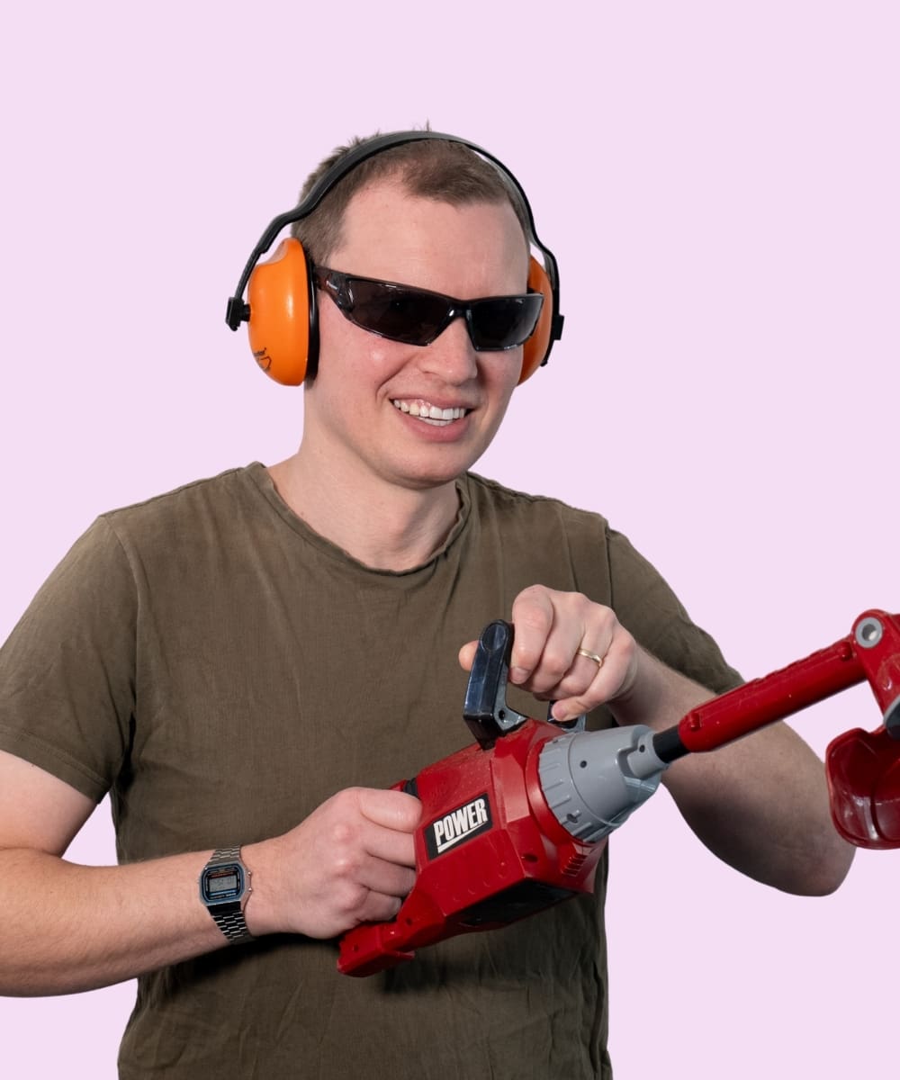 Matt wearing protective glasses, ear protection and holding a power tool.